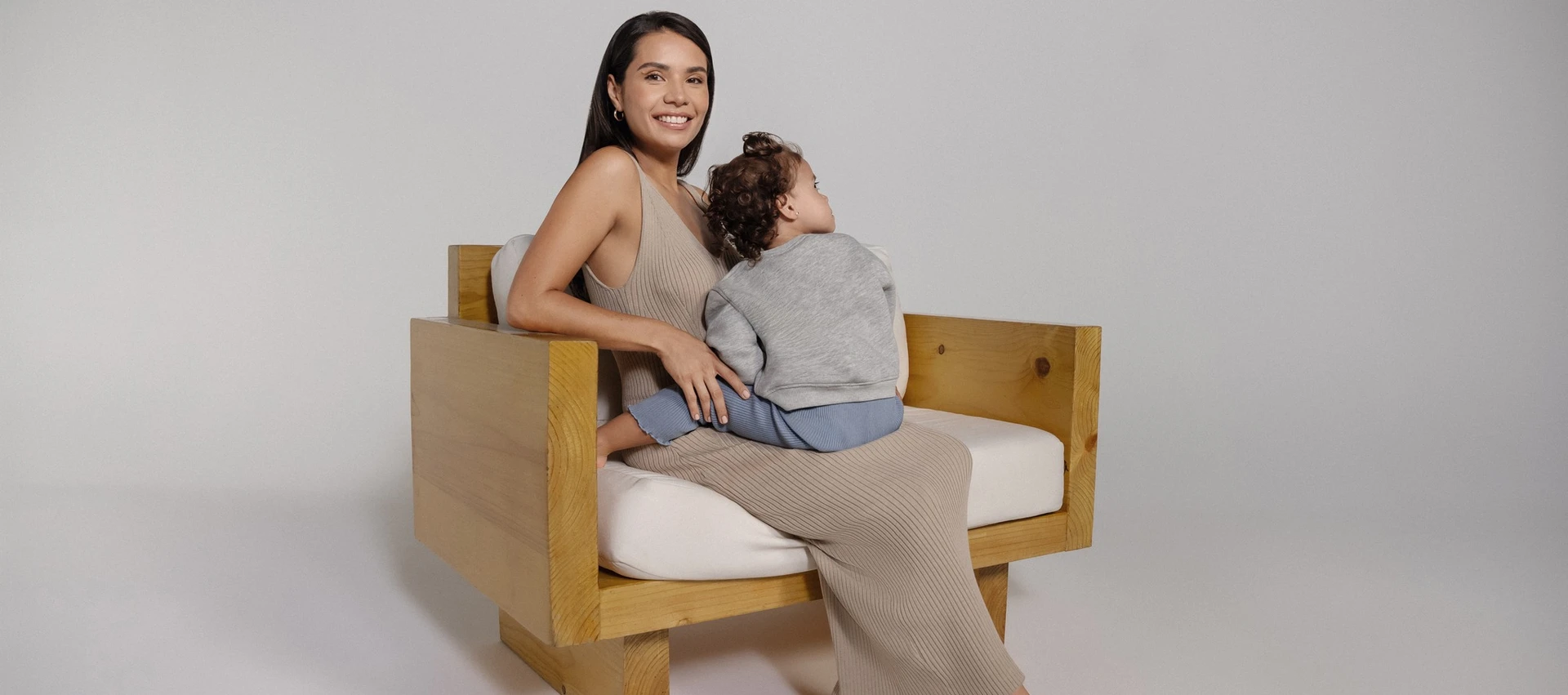 En Mia® kvinde sidder på en træsofa med en baby