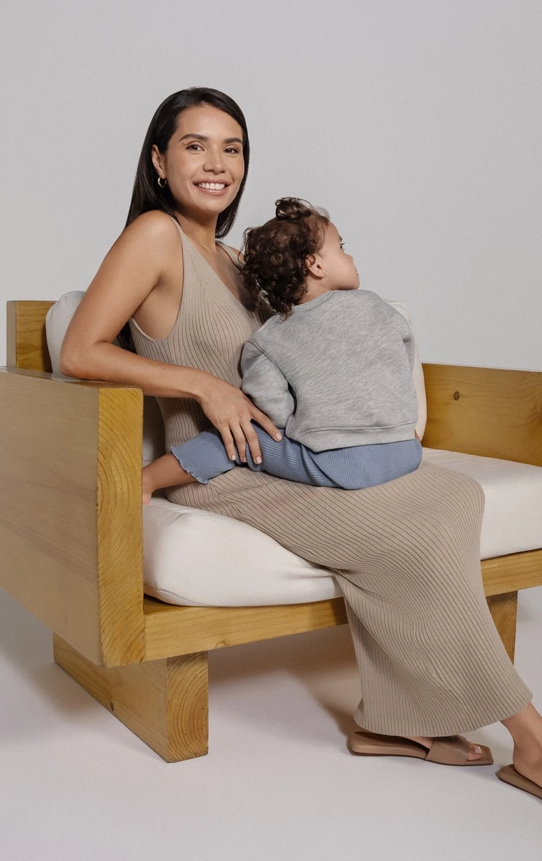 Une femme Mia® assise sur un canapé en bois avec un bébé