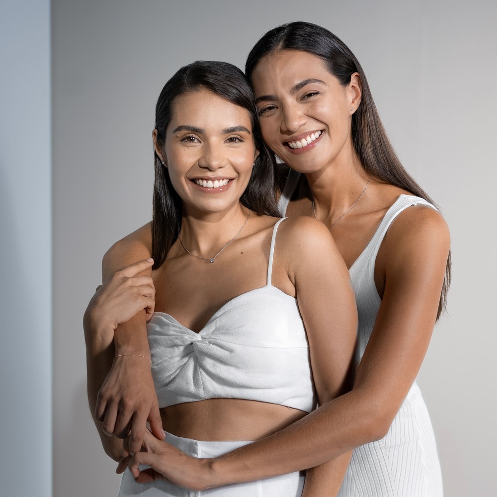 Two women hugging in white dresses